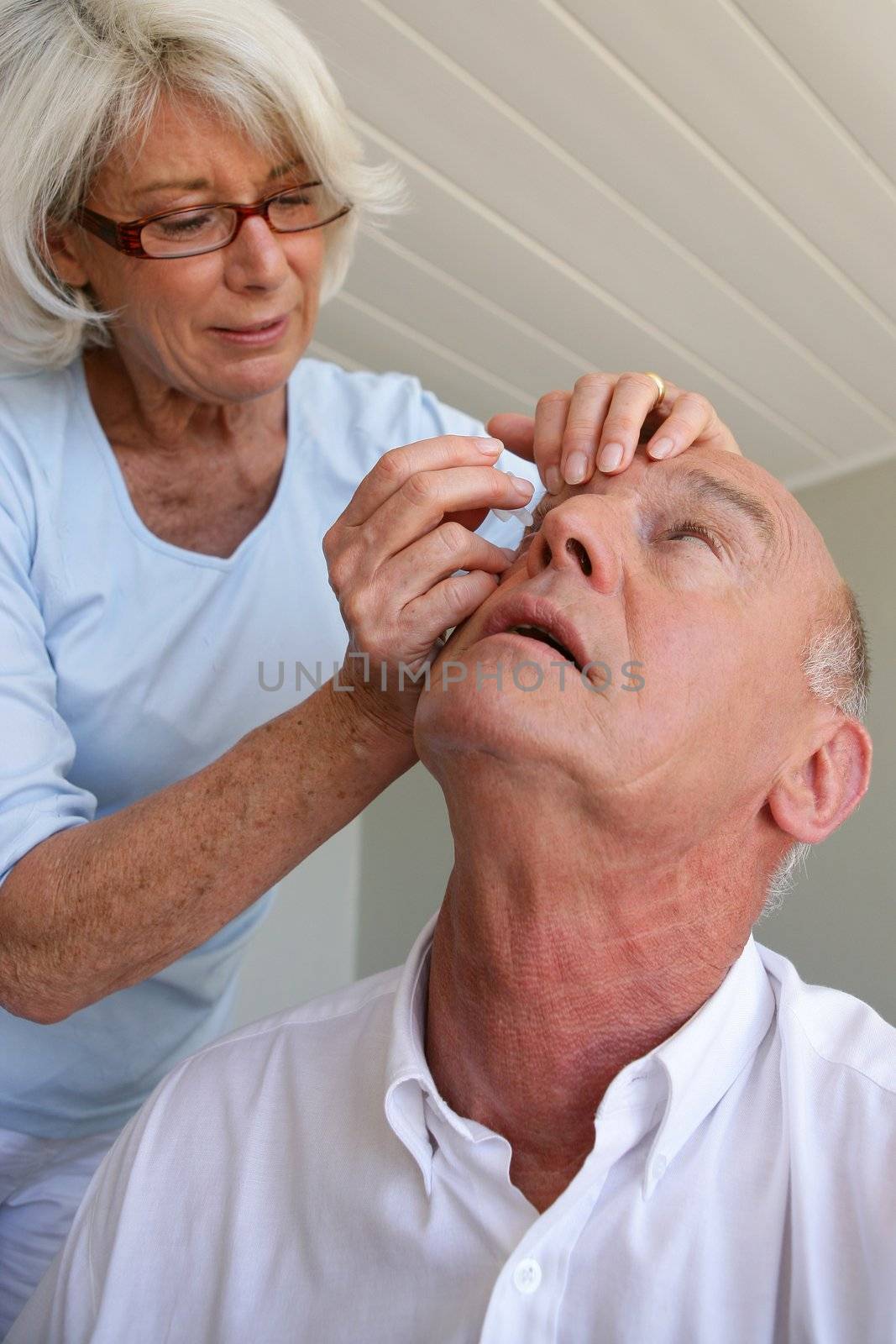 Woman helping husband with contact lenses by phovoir