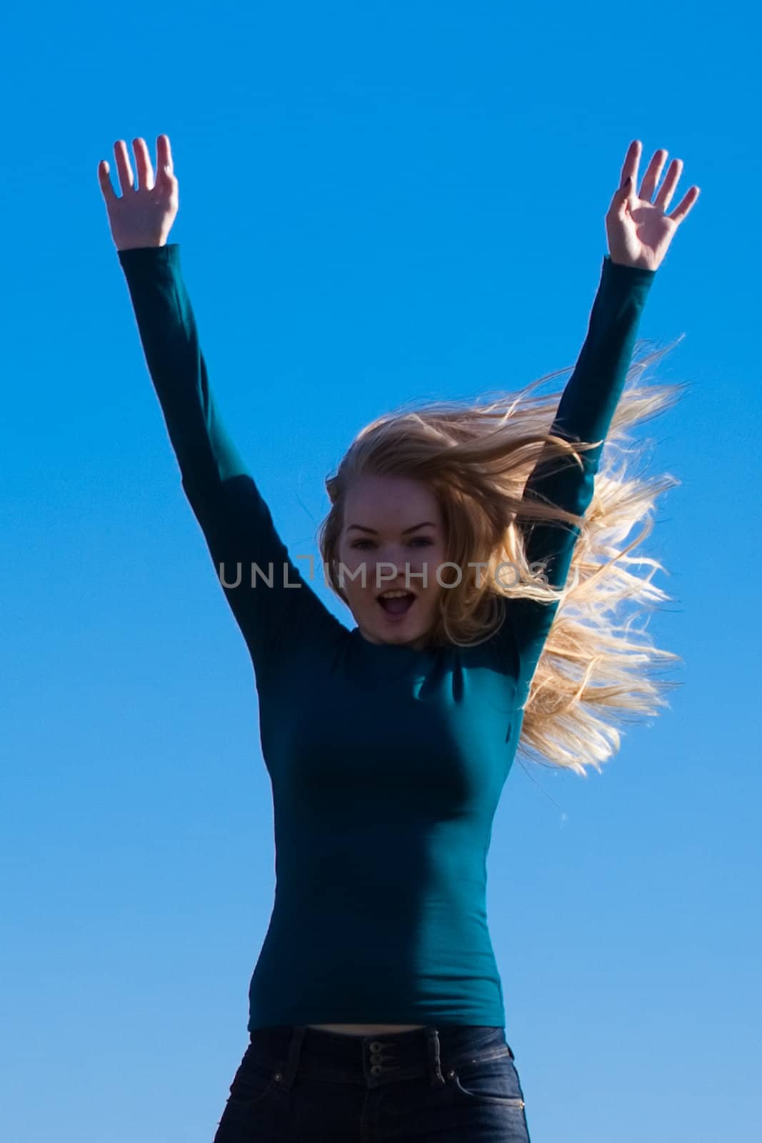 young beautiful woman jumping into the field against the sky