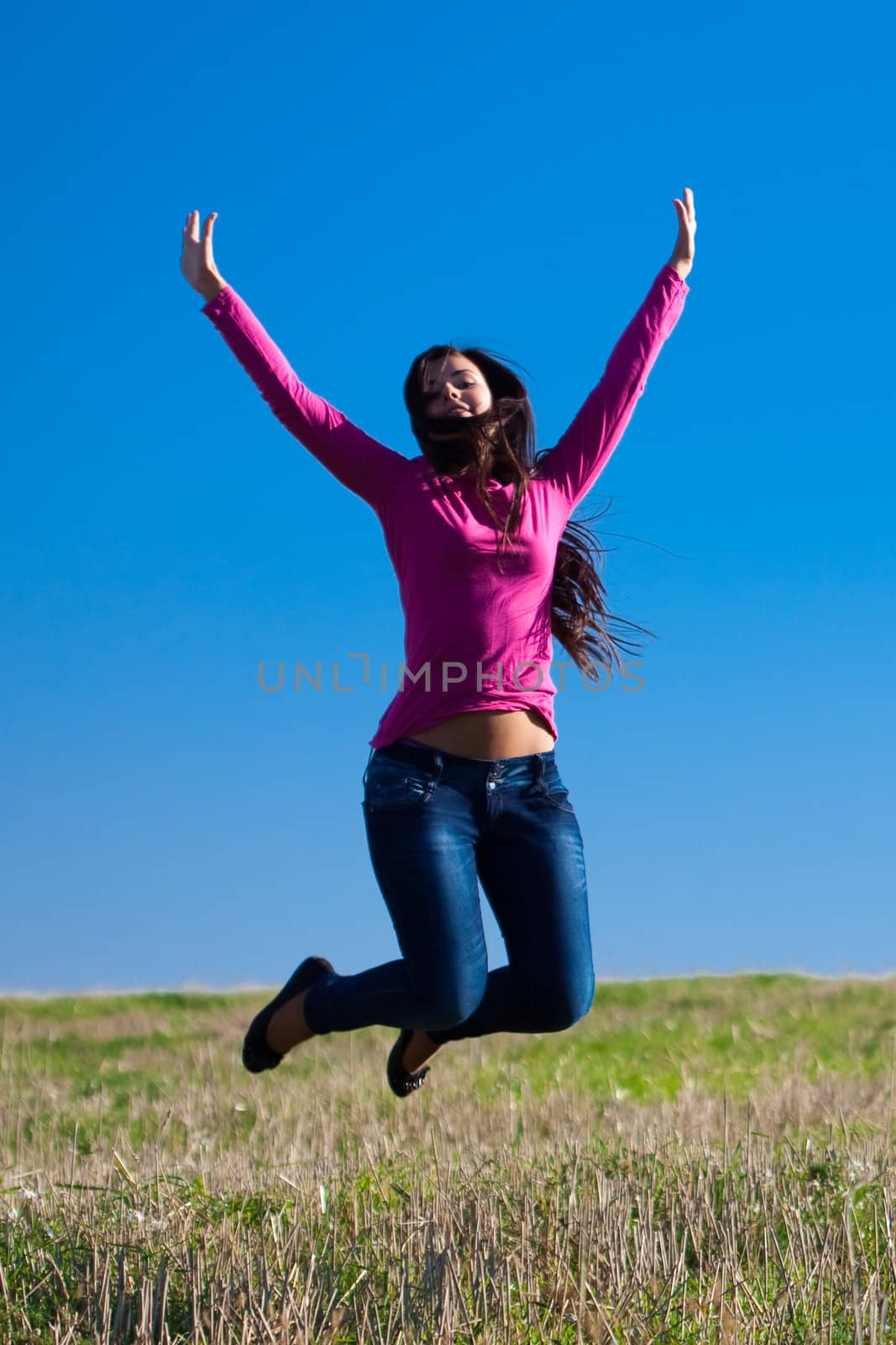 young beautiful woman jumping into the field against the sky