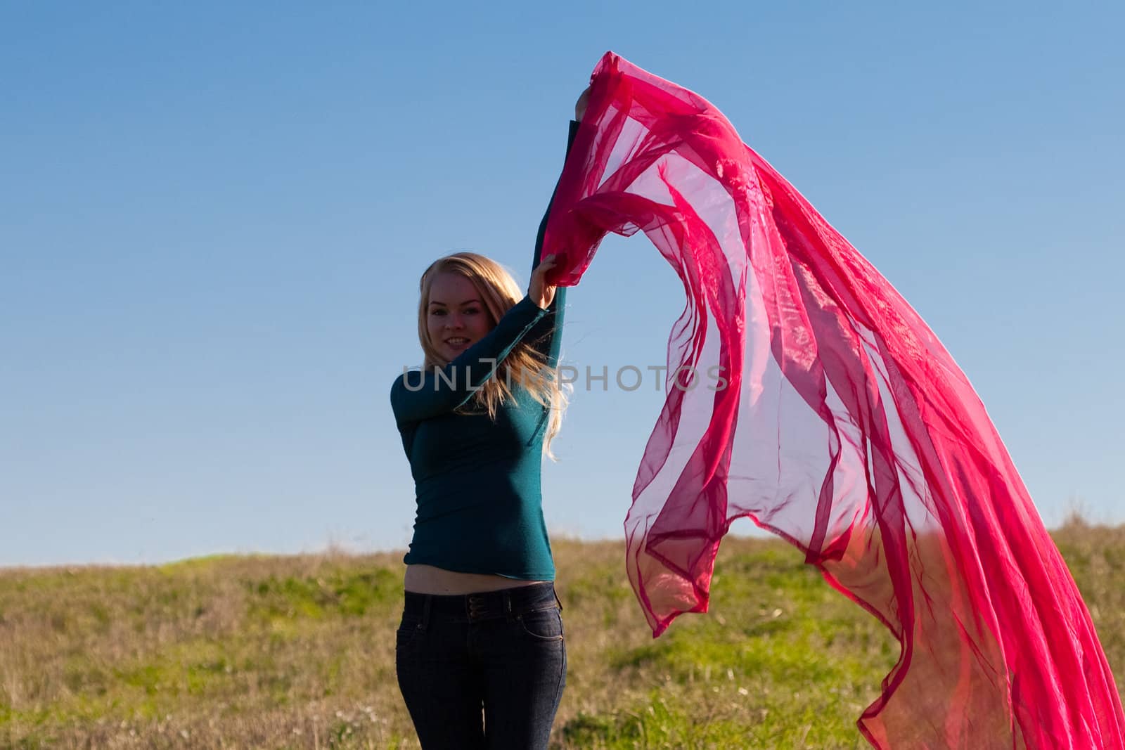 young beautiful woman jumping with tissue into the field against the sky