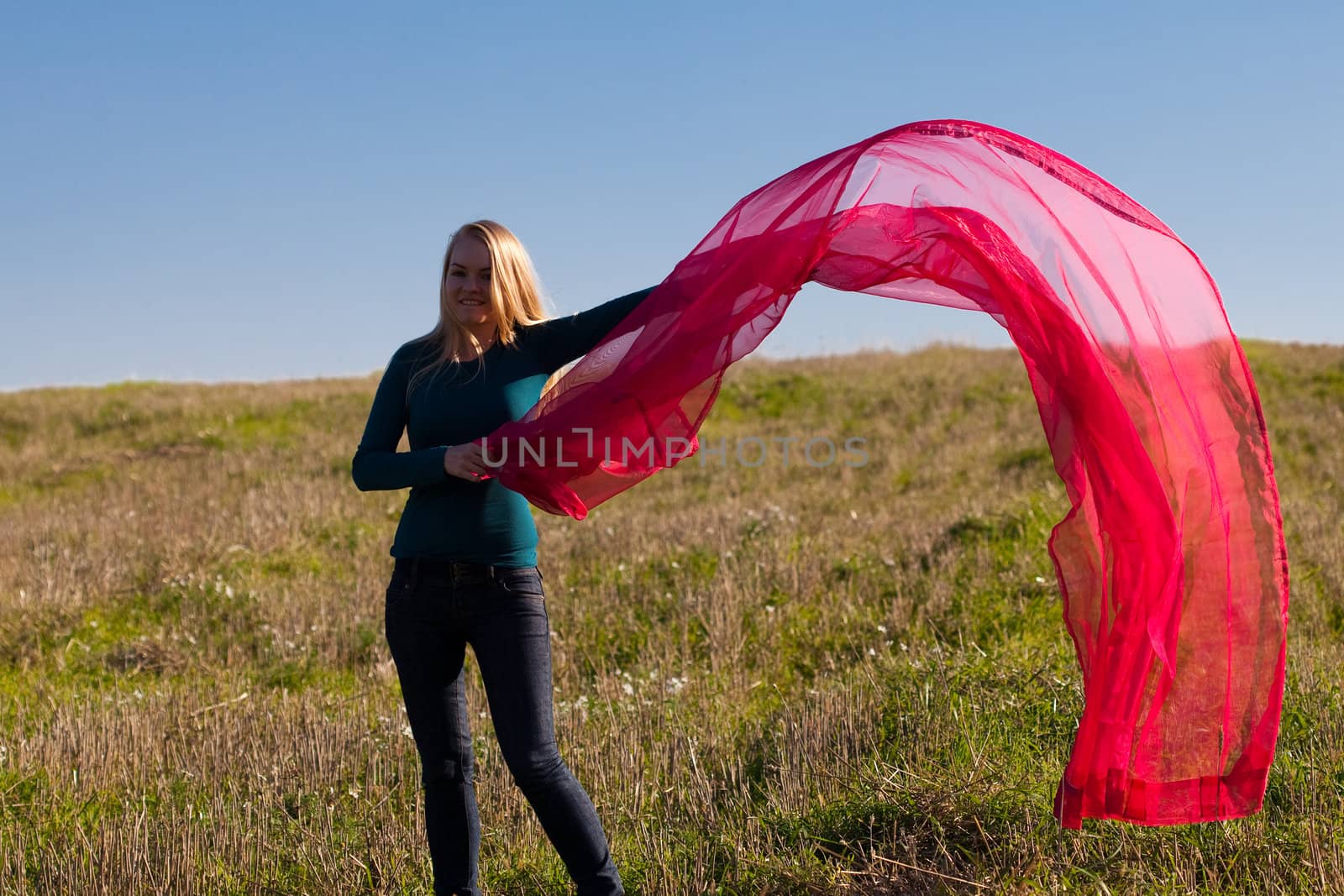 young beautiful woman jumping with tissue into the field against the sky