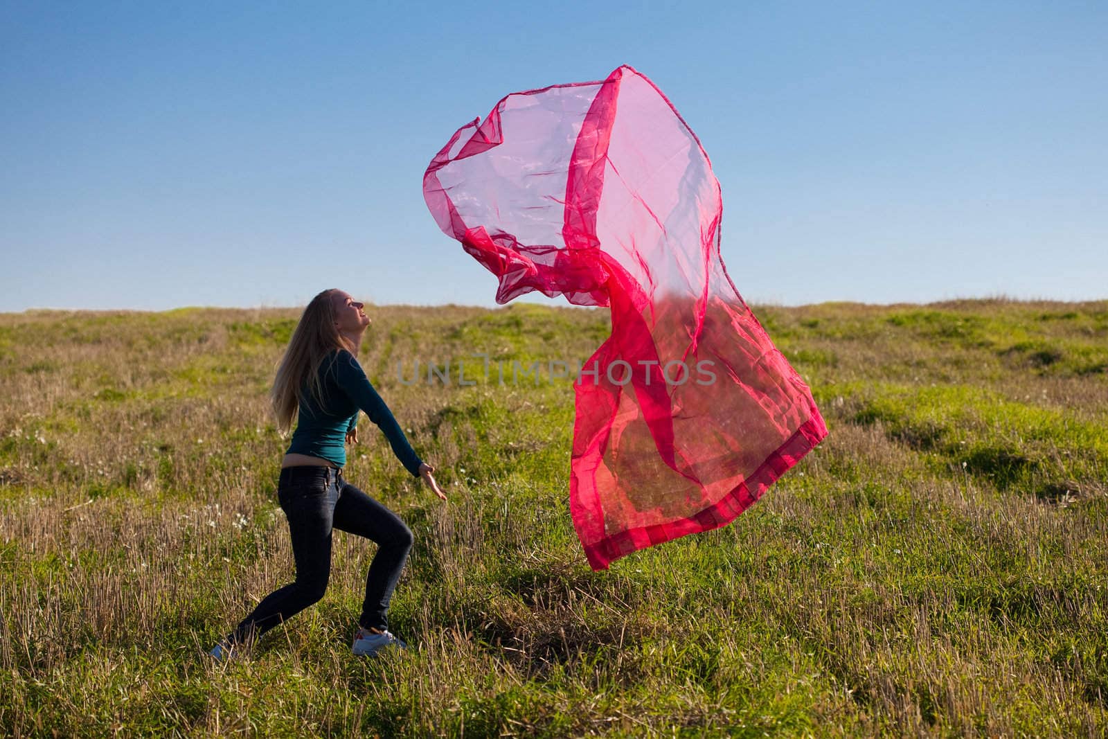 young beautiful woman jumping with tissue into the field against the sky