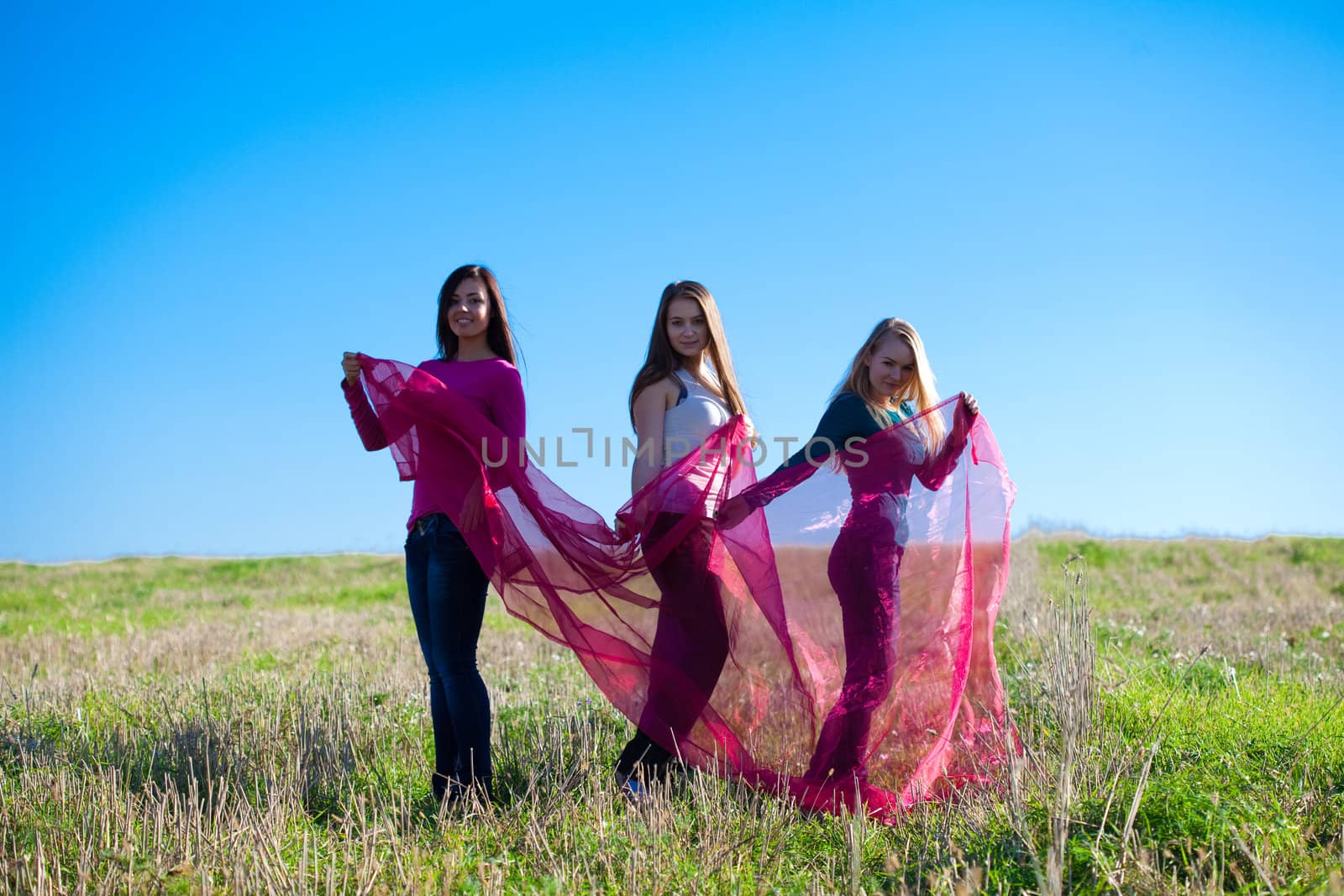 three young beautiful woman standing with tissue into the field against the sky