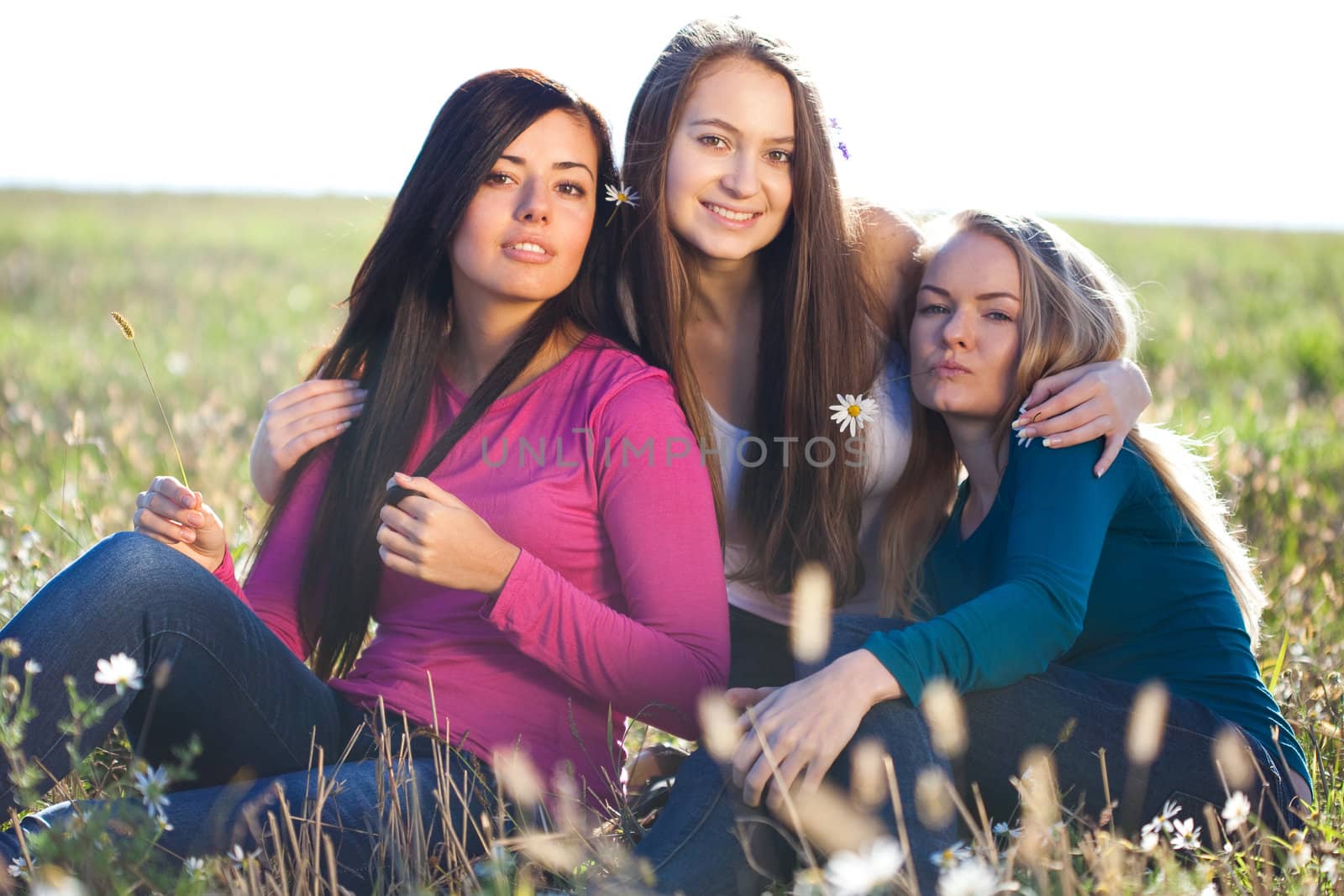 three young beautiful woman sitting in a field on the  sky backg by jannyjus