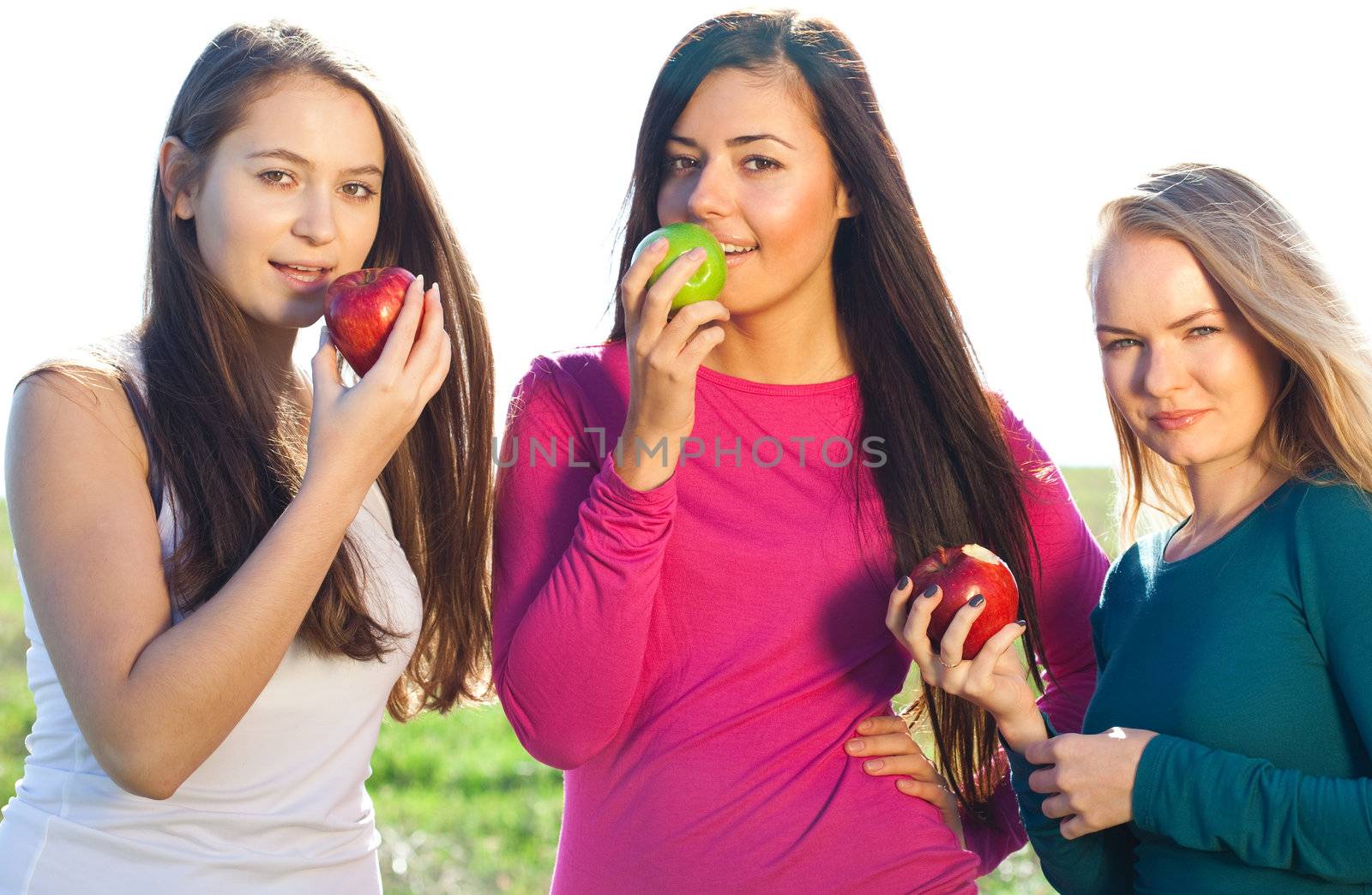 portret of three young beautiful woman with apple on the  sky background 