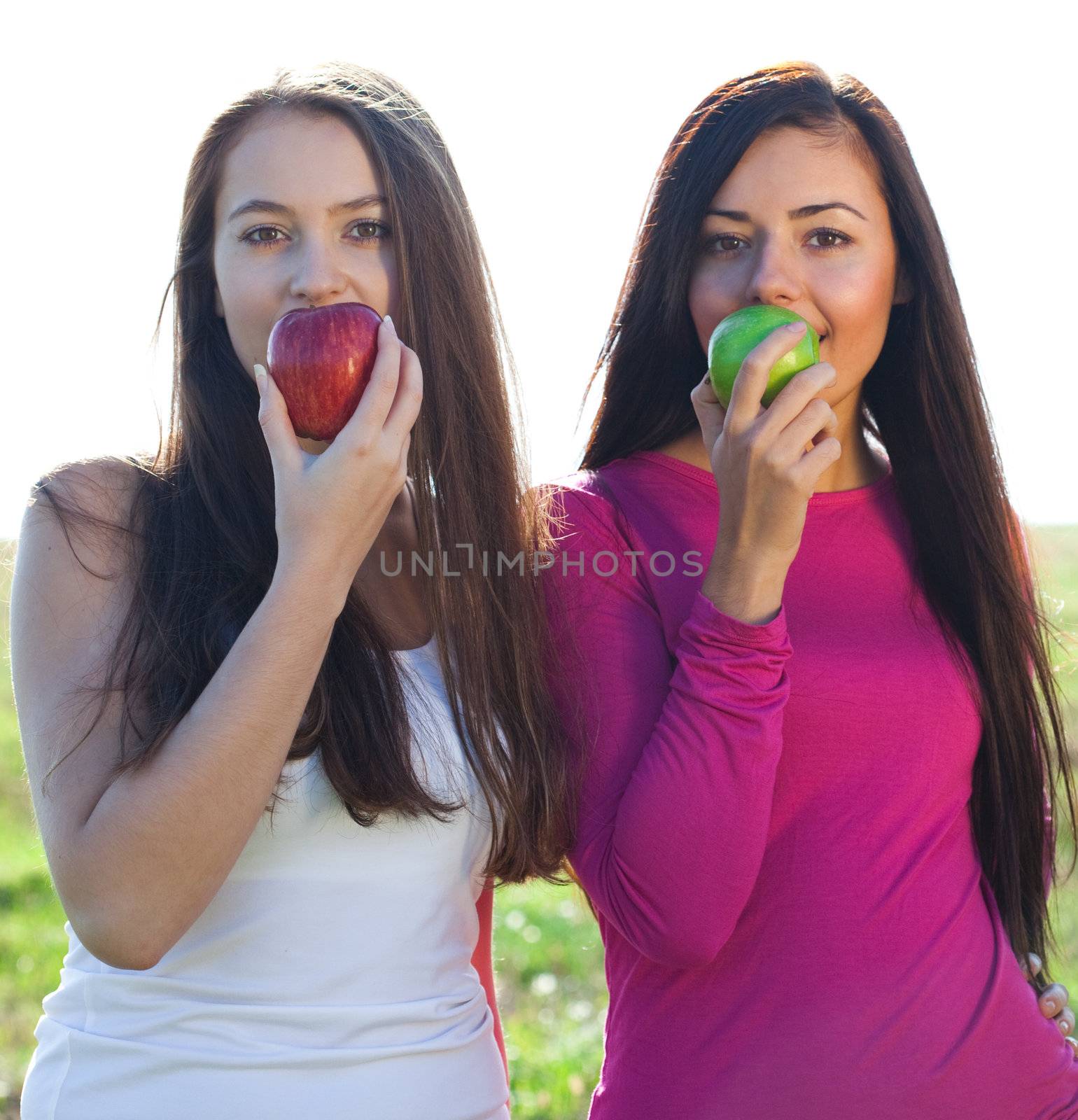 portret of two young beautiful woman with apple on the  sky back by jannyjus