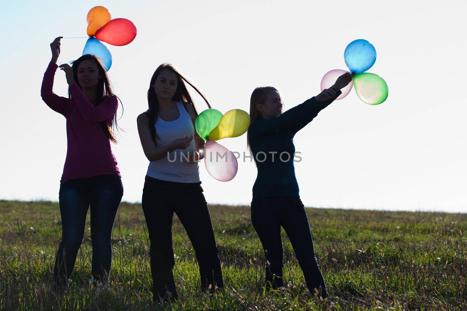 three young beautiful woman with balloons into the field against by jannyjus