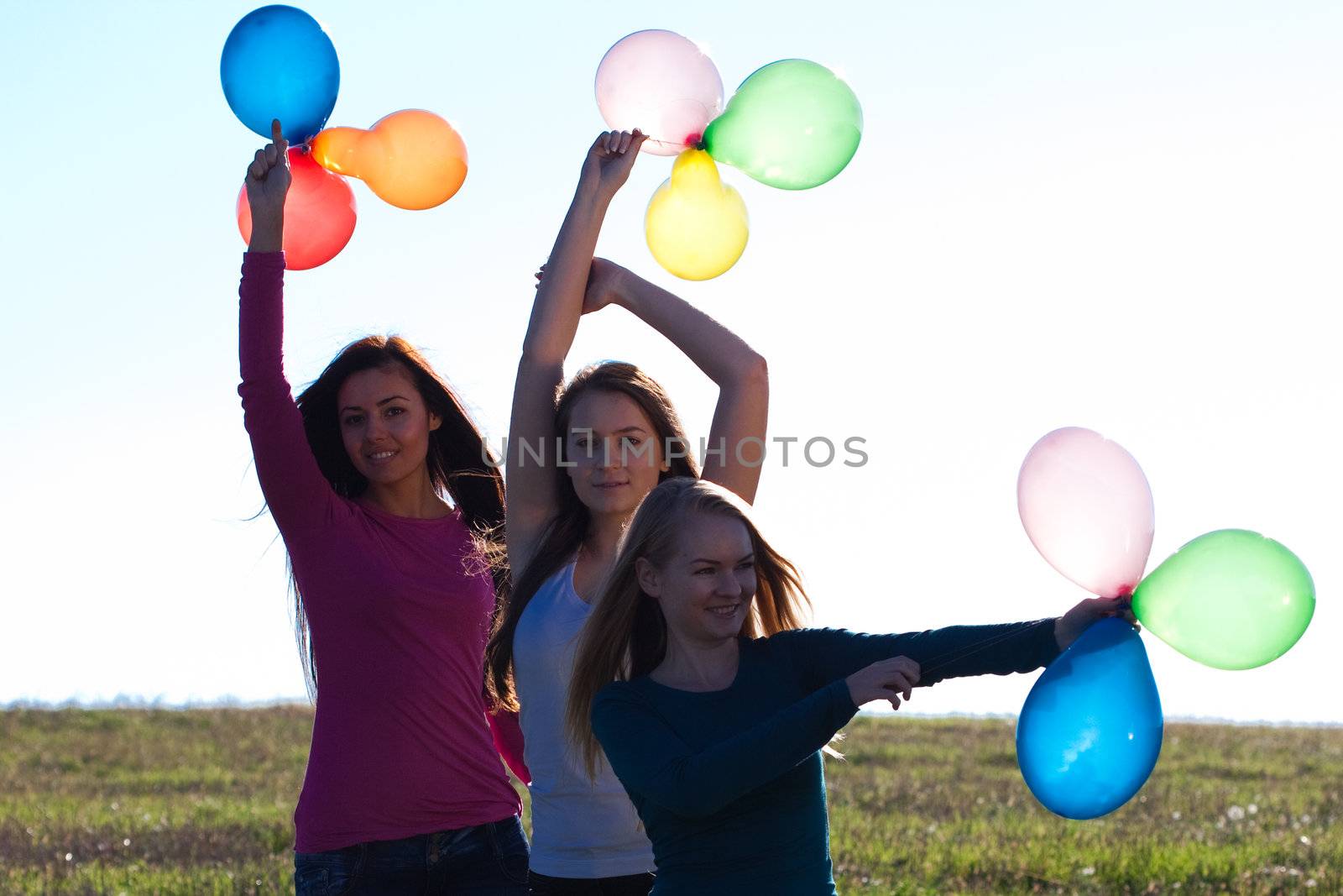 three young beautiful woman with balloons into the field against by jannyjus