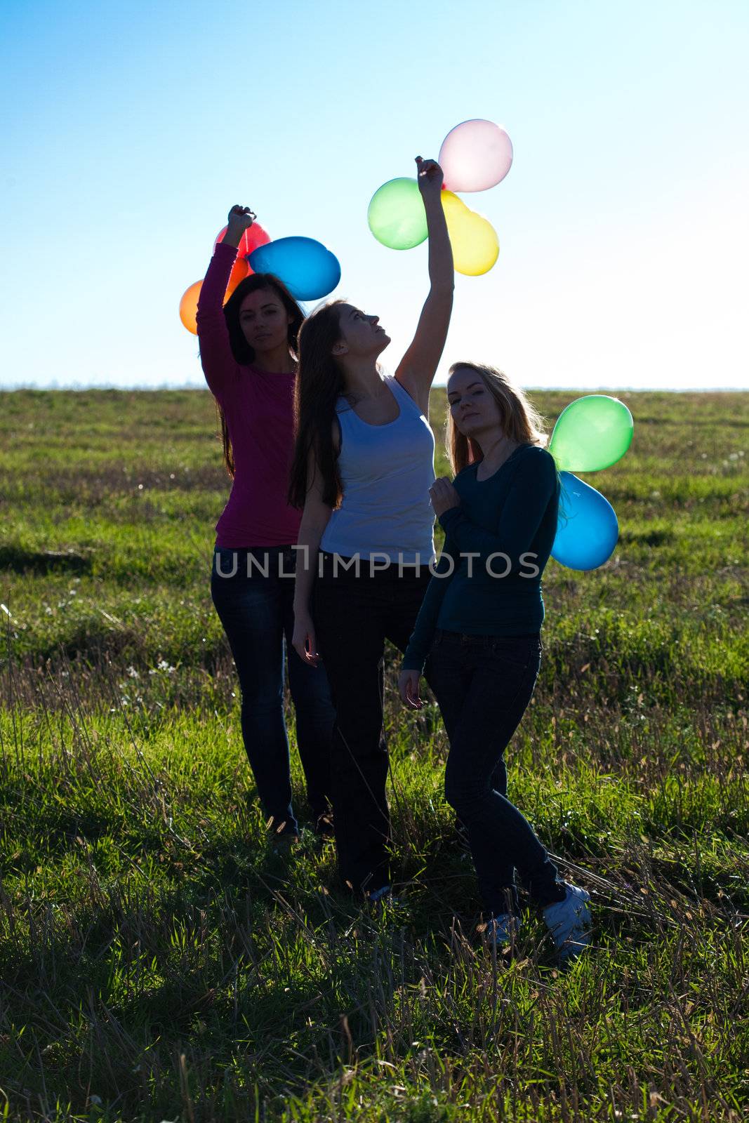 three young beautiful woman with balloons into the field against by jannyjus