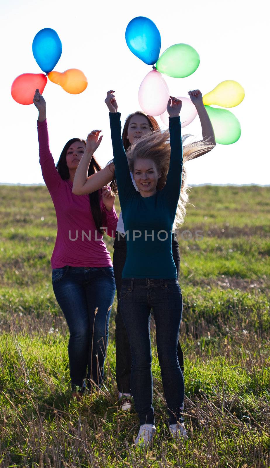 three young beautiful woman with balloons into the field against by jannyjus