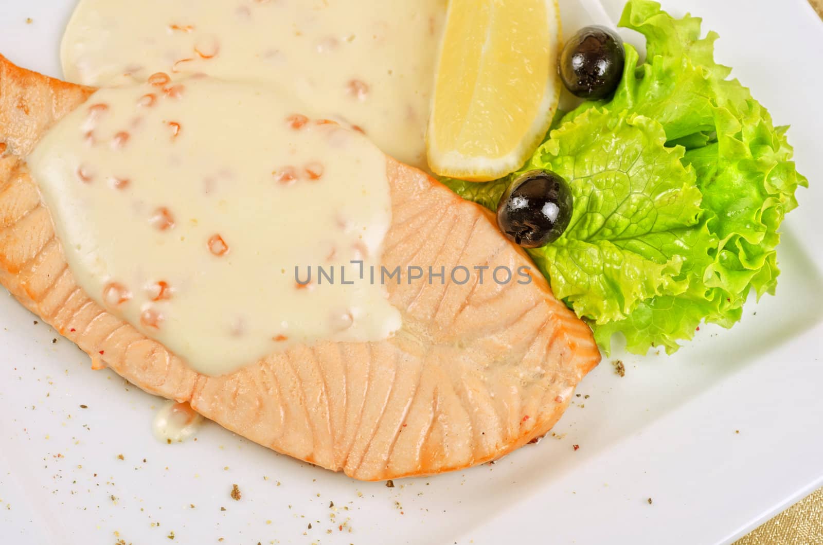 Grilled salmon steak with sauce of cheese and caviar, greens, lemon and olive