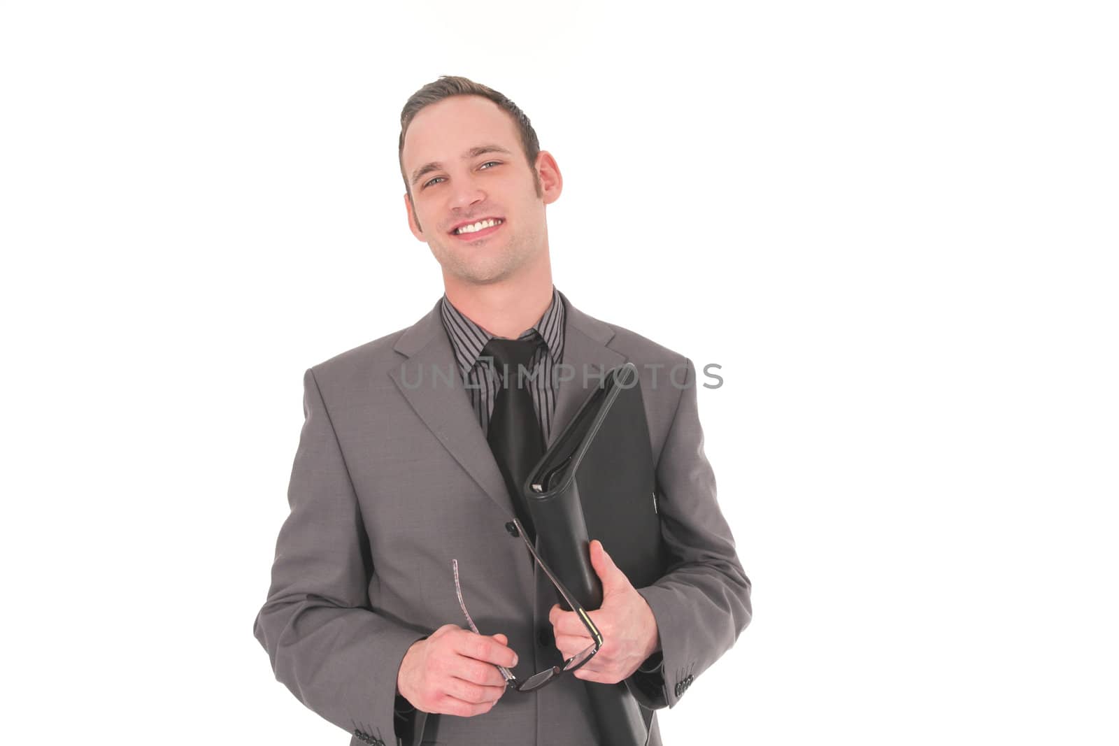 Smiling businessman with glasses in his hand a a black leather file under his arm standing looking at the camera isolated on white