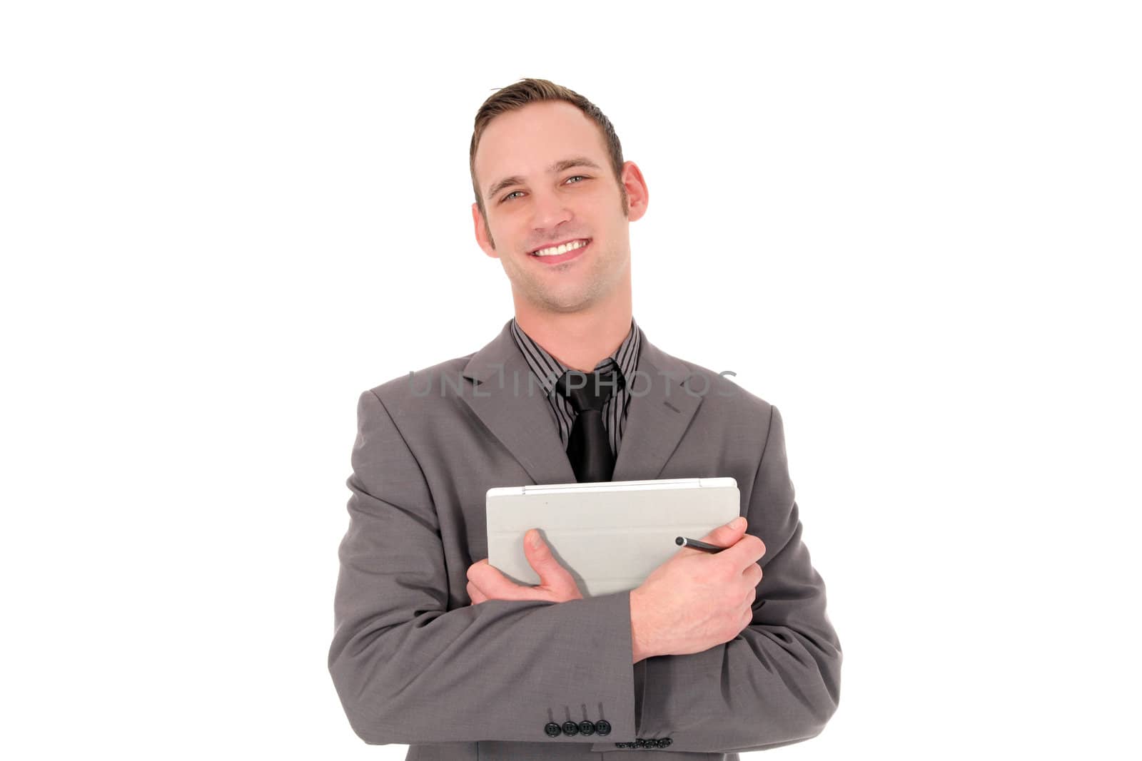 Young successful businessman standing smiling at the camera while holding a tablet computer in his folded arms, isolated on white