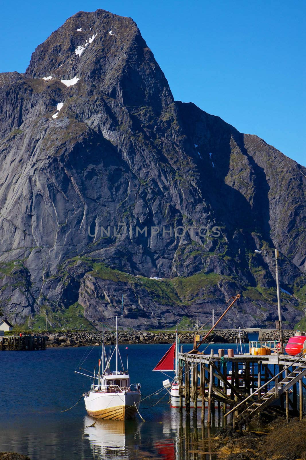 Fishing boat in town of Reine on Lofoten islands with high peak above fjord