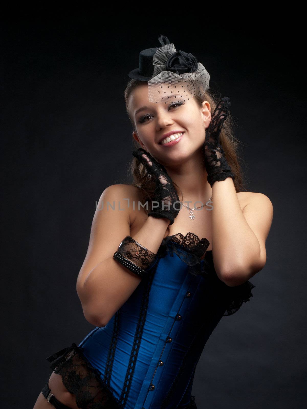 Half body portrait of attractive young woman in vintage style dance clothes with small top hat; studio background.