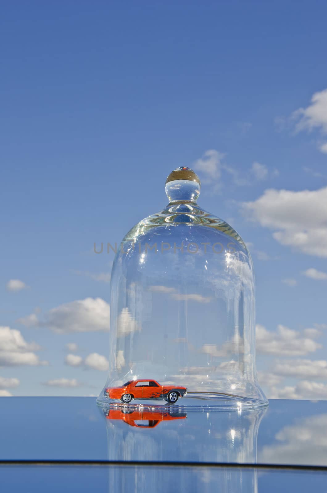 red car toy on mirror in space and glass bell