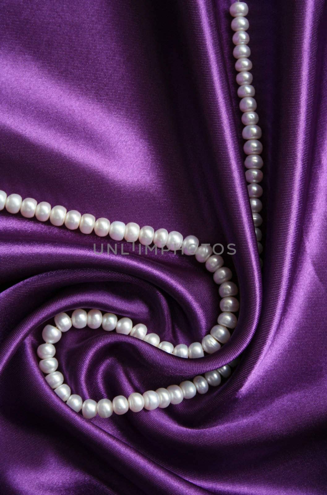 White pearls on a lilac silk as background 