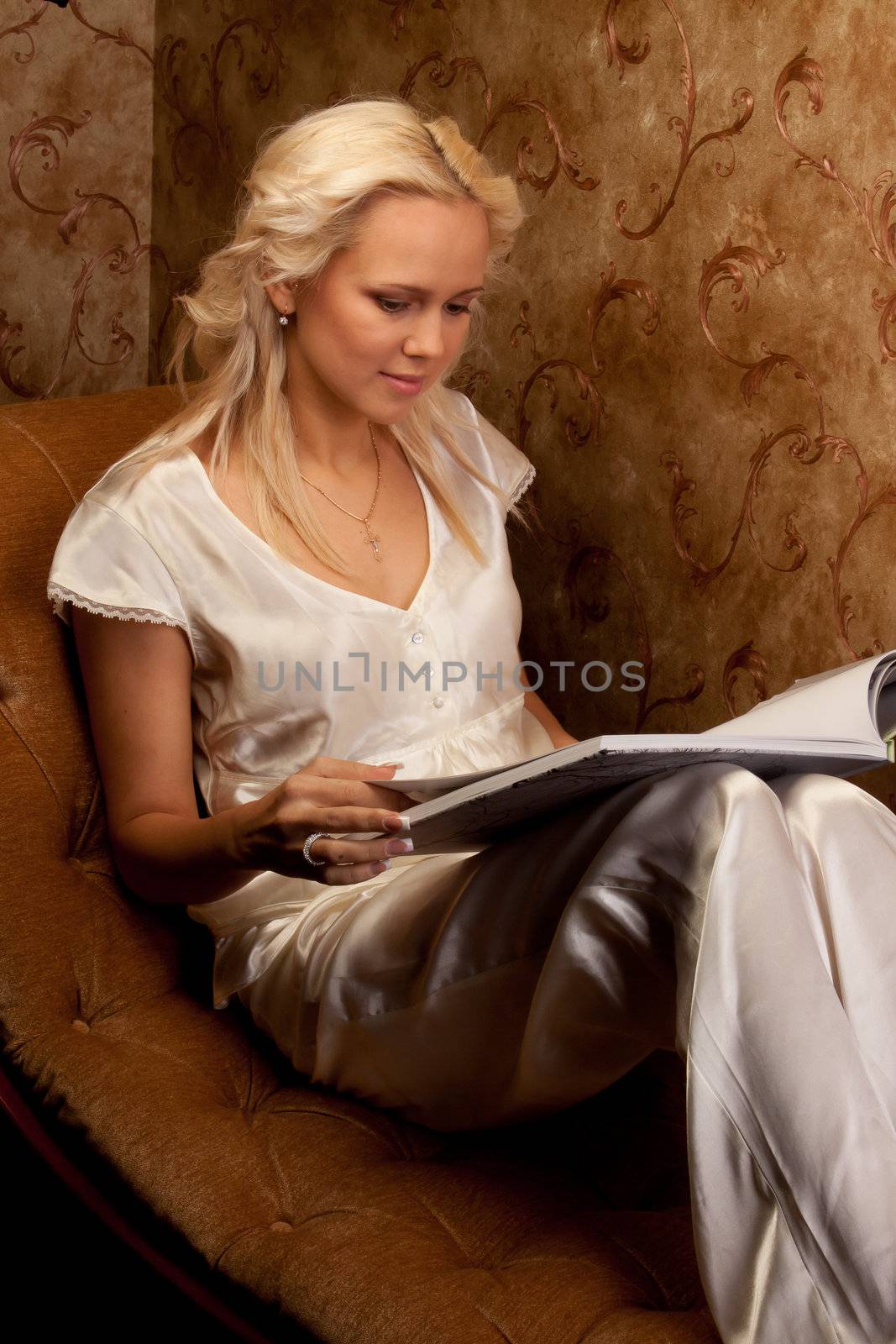 Young and beautiful girl reading a book cover in black sitting on a couch in his home