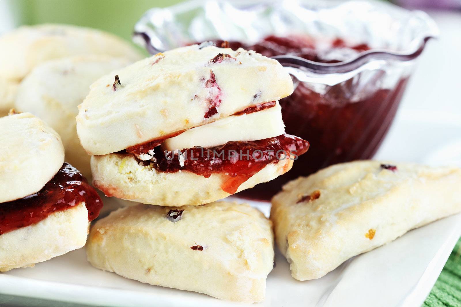 Closeup of freshly baked scones with butter and strawberry preserves. Selective focus with shallow depth of field.