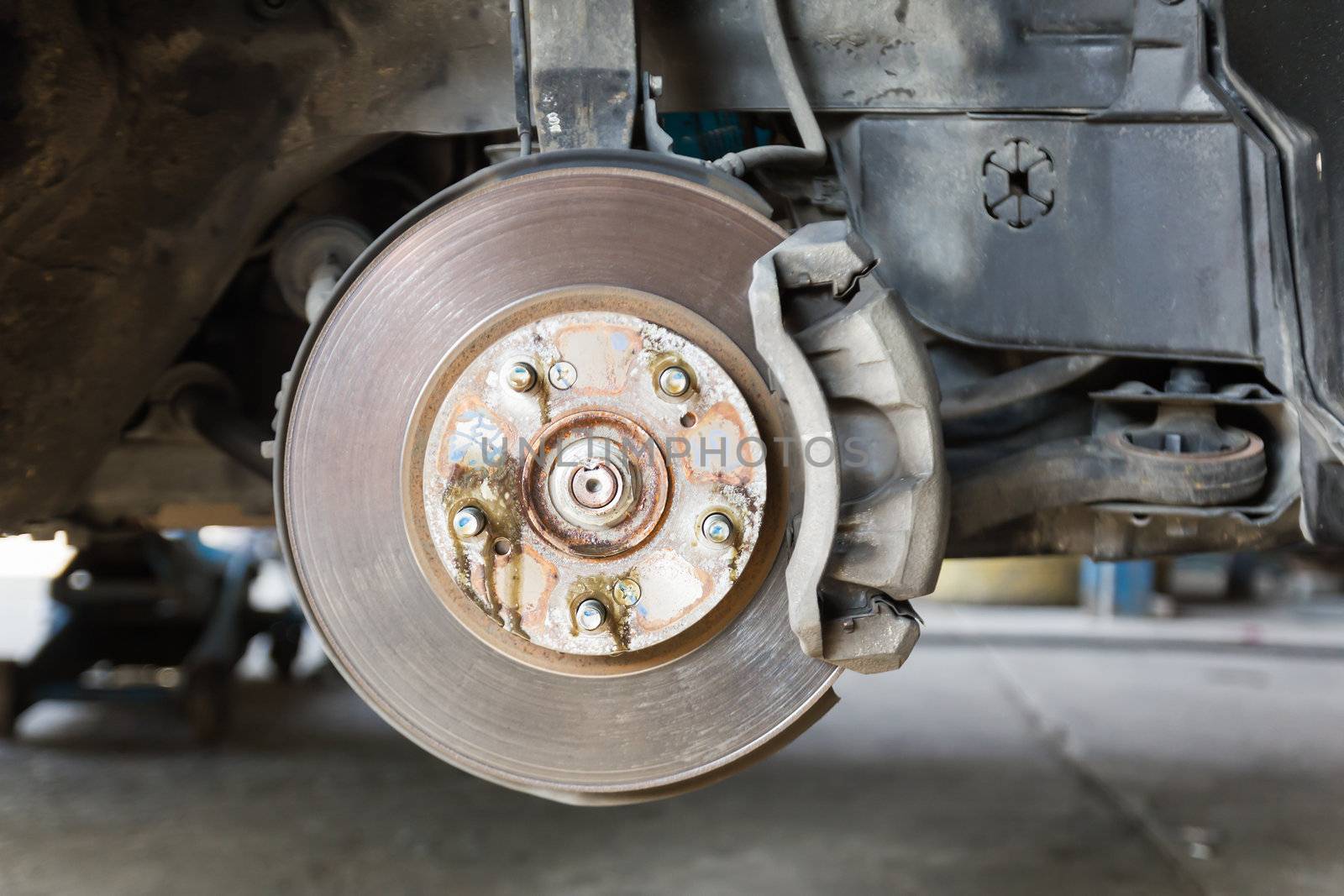 Front disk brake on car in process of damaged tyre replacement. The rim is removed showing the front rotor and caliper.