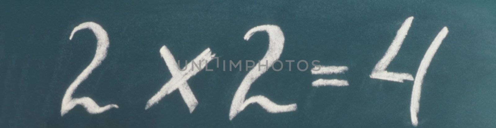 A chalkboard on white with "2 * 2=4" written on it.