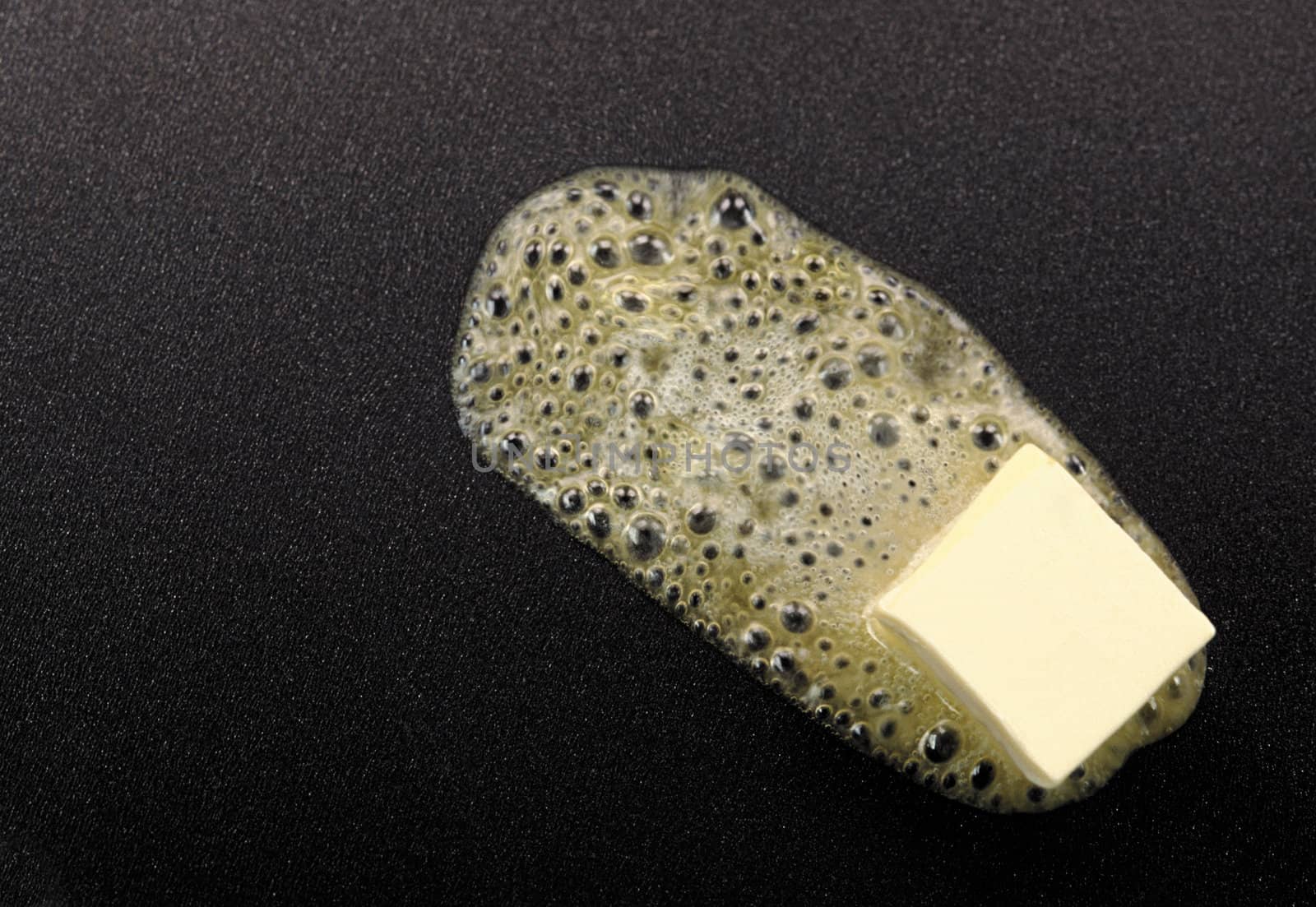 Piece of butter melting on non-stick frying pan