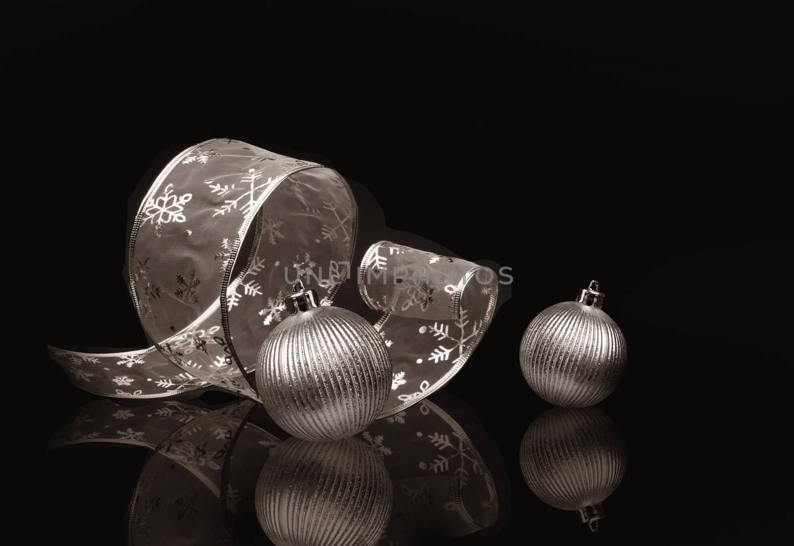 Sepia toned silver ribbon and Christmas balls on dark background