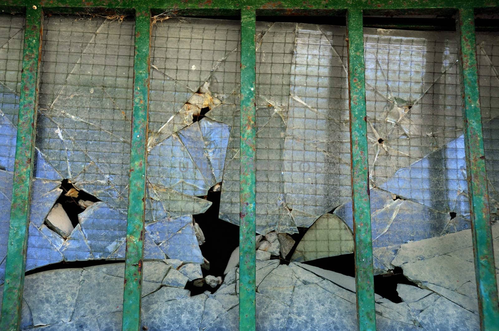 Broken thick glass behind iron bars. Abstract background texture.