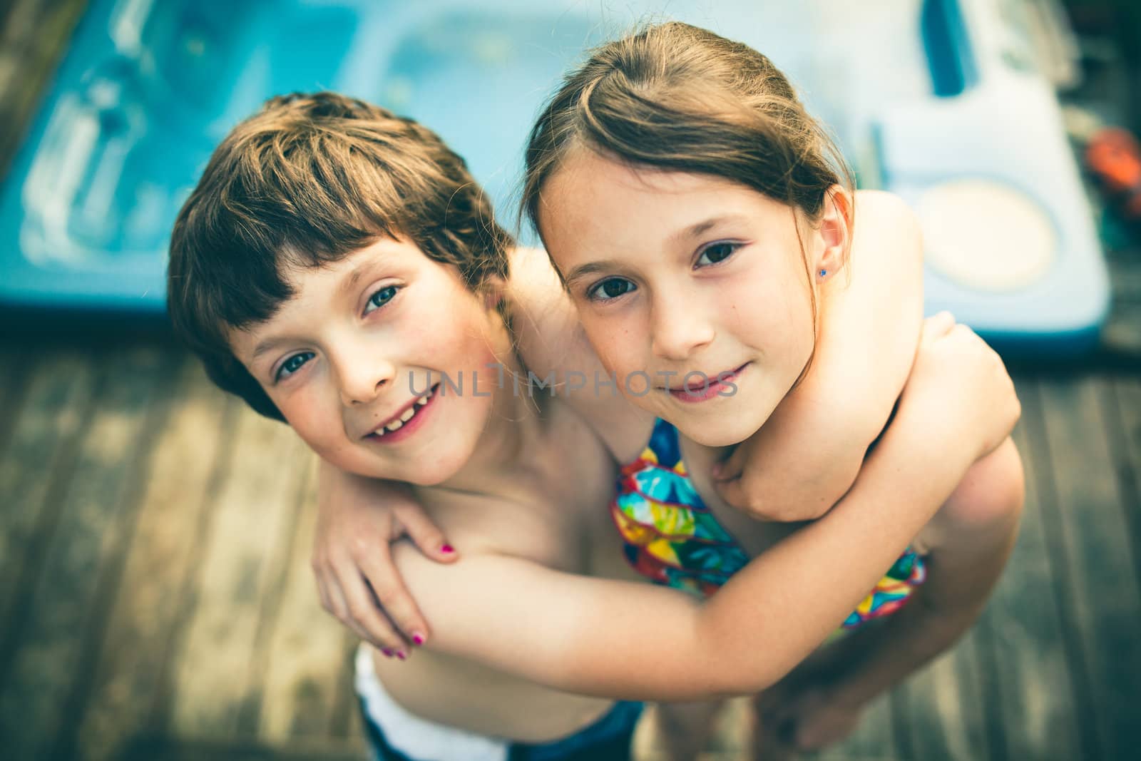 Brother and sister hugging in bathing suit in front of a jacuzzi