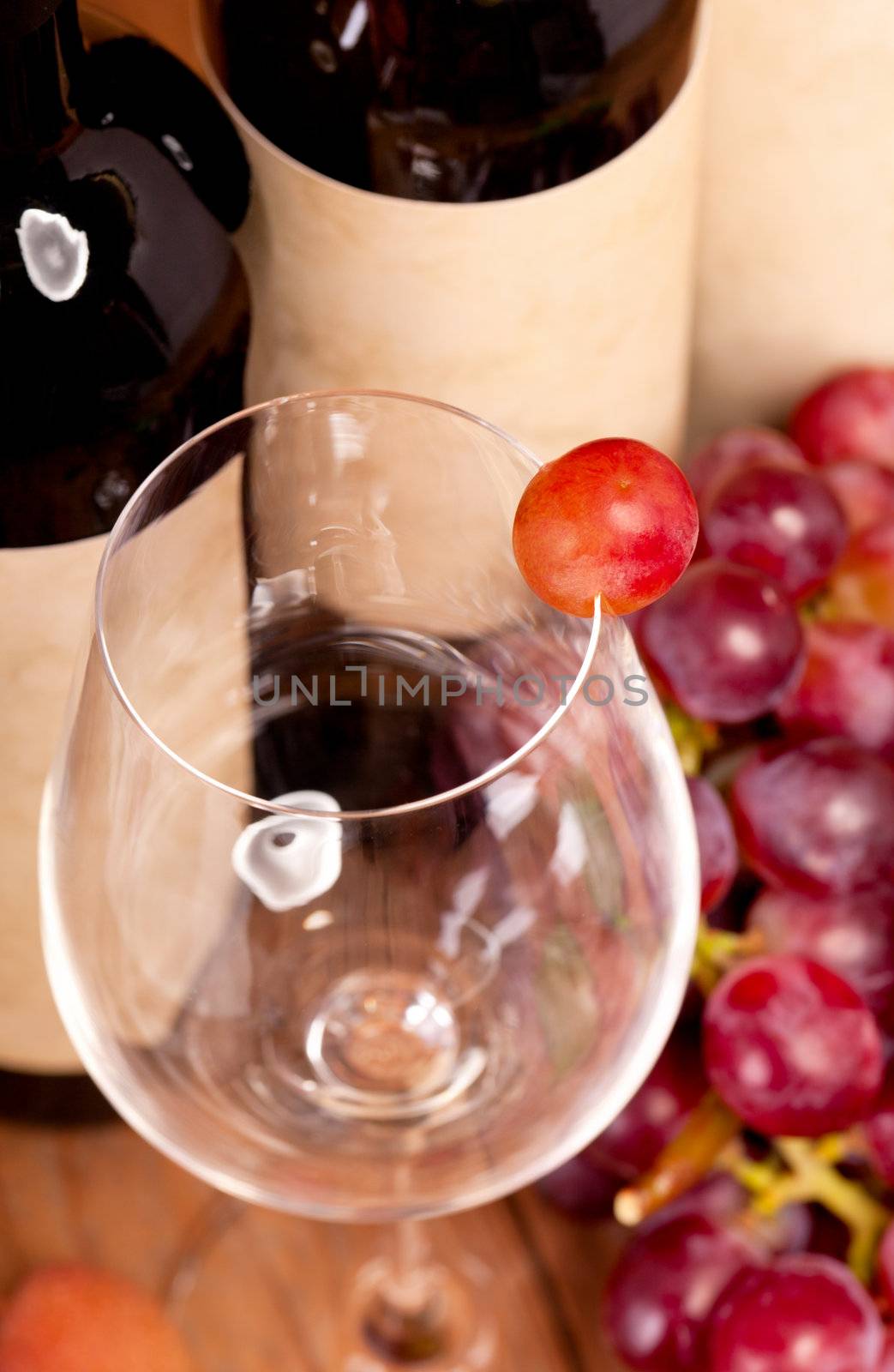 macro shot of one red grapes berry in glass. on wine bottle back by motorolka