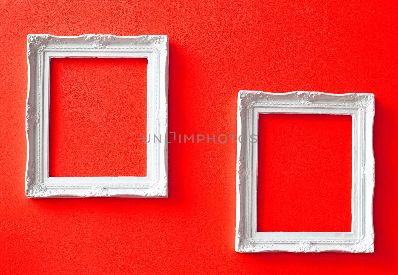 Two white vintage frames on red wall 