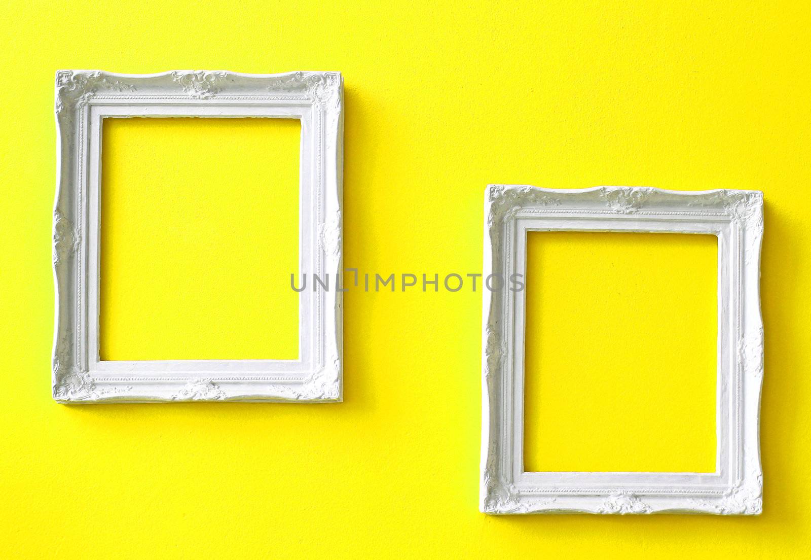 Two white vintage frames on yellow wall  by nuchylee