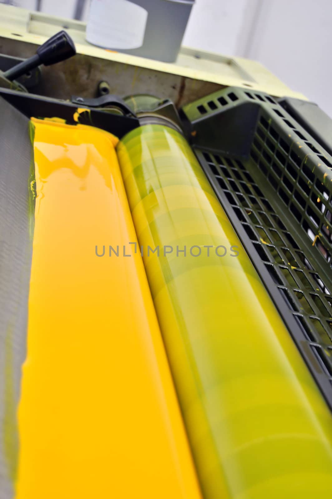 Printing press with cmyk yellow ink paint detail. Selective focus.