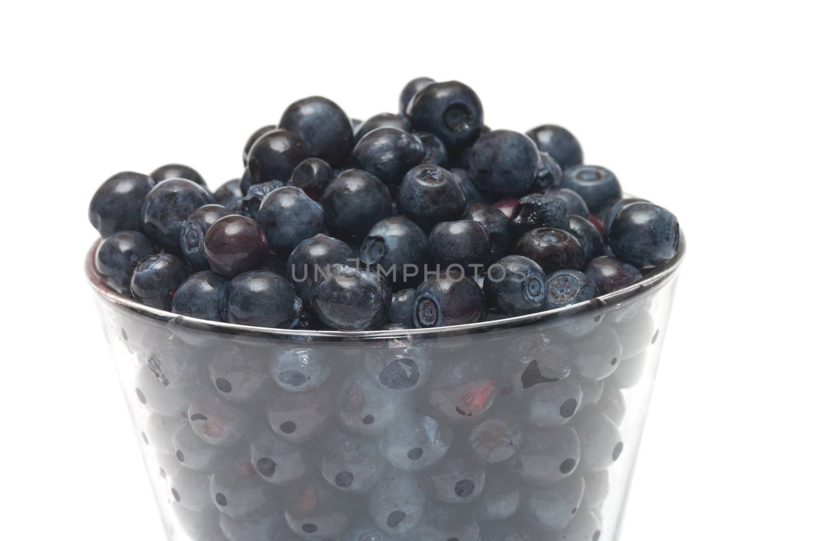 Glass filled by a bilberry it is isolated on a white background.