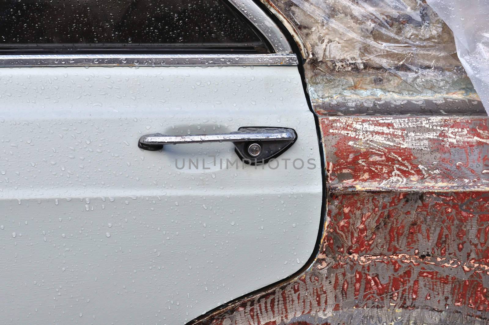 Vintage car window and scraped metal door with raindrops. Background texture.