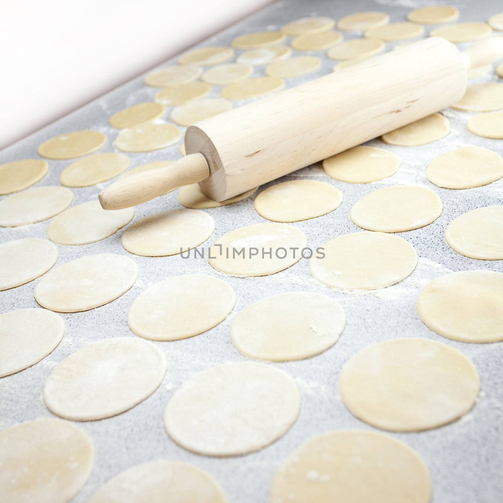 round shape of the dough and rolling pin with flour on the table by jannyjus