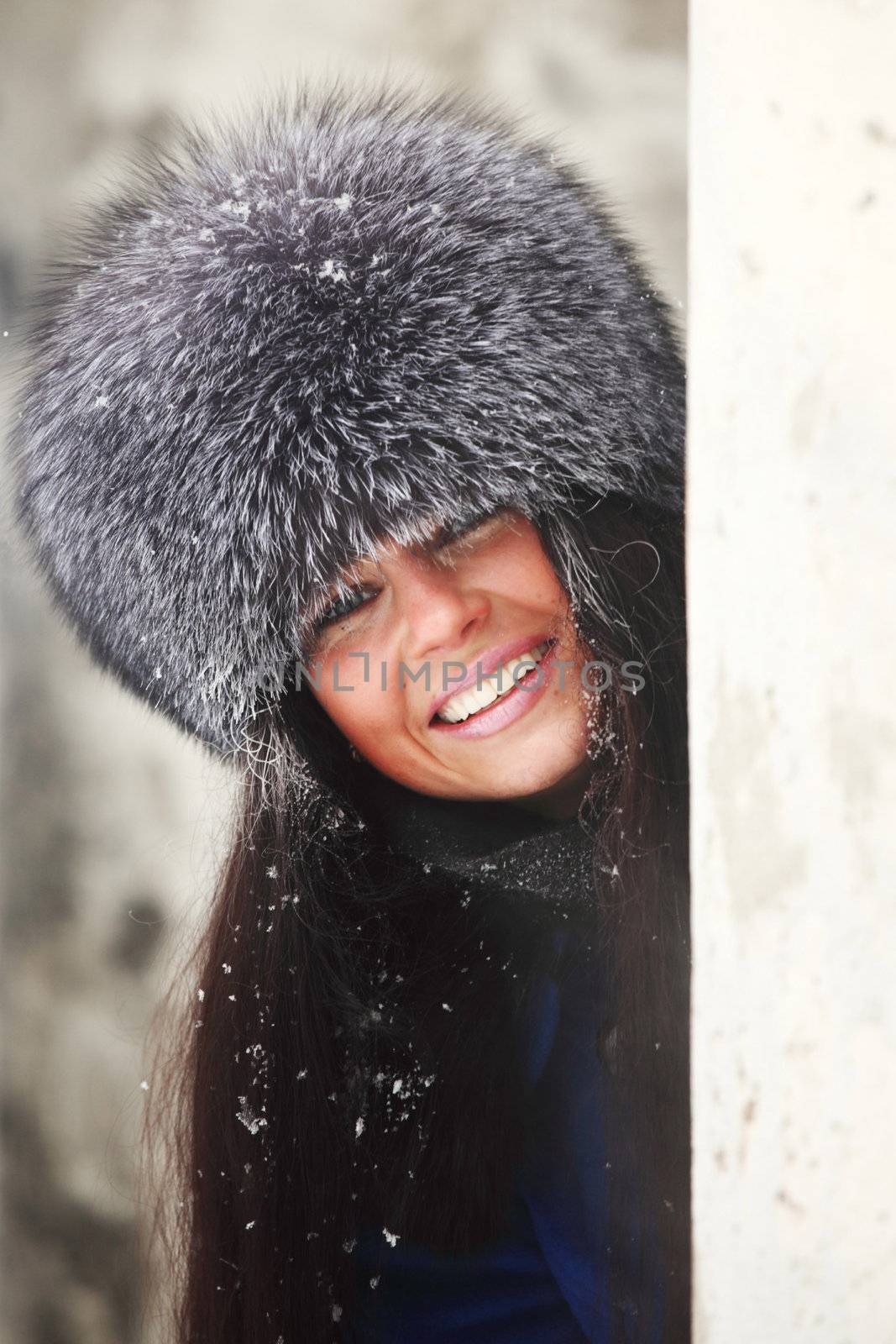  woman in fur hat hide behind column