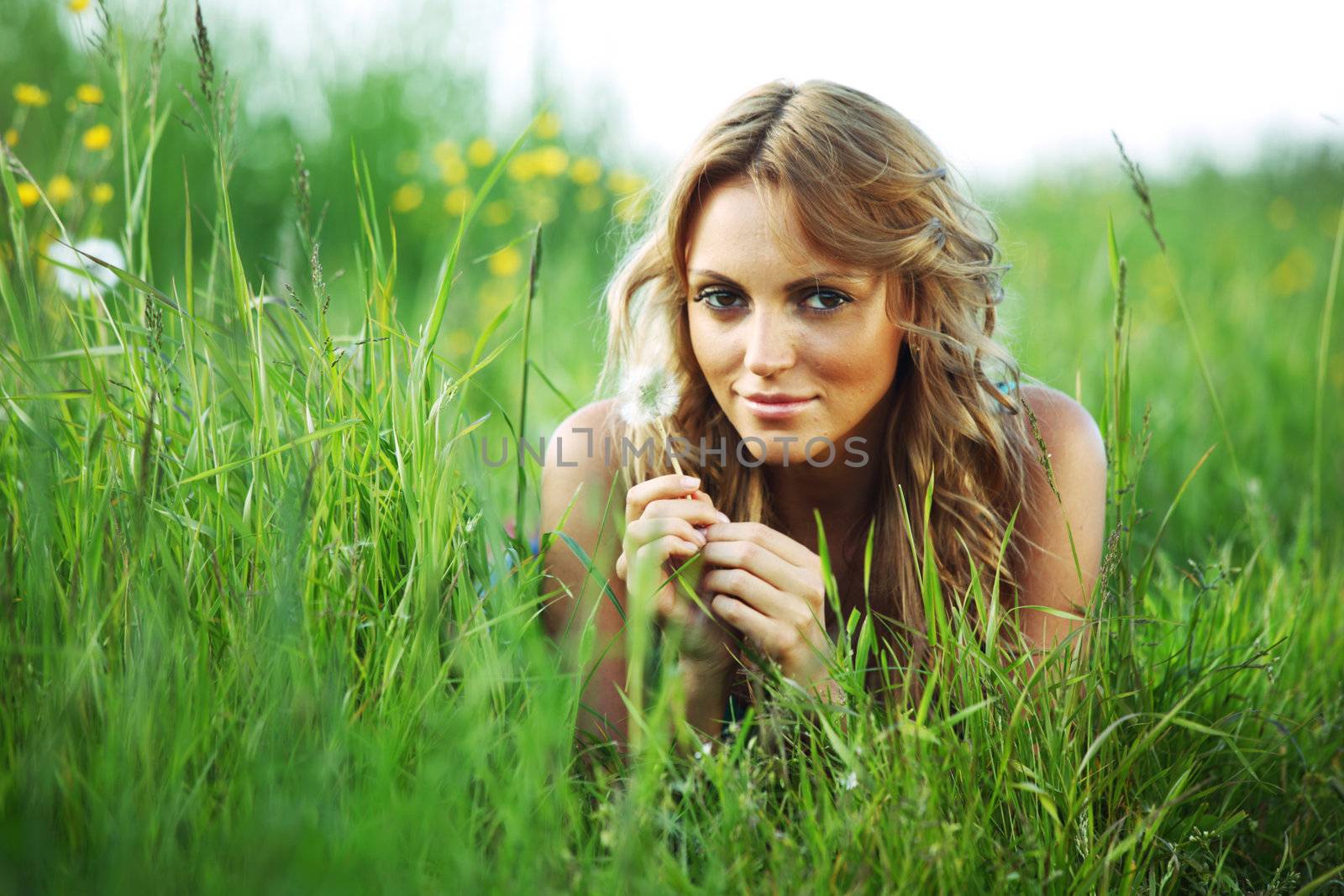 girl blow on dandelion on green field