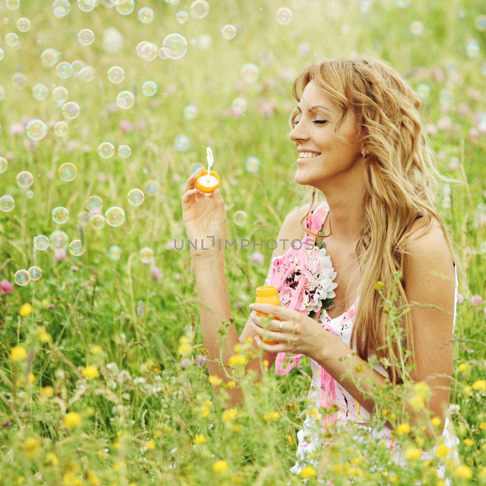  Blonde starts soap bubbles in a green field