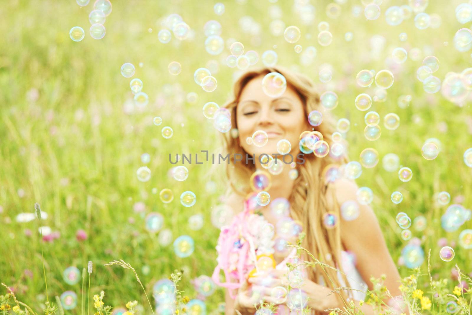  Blonde starts soap bubbles in a green field