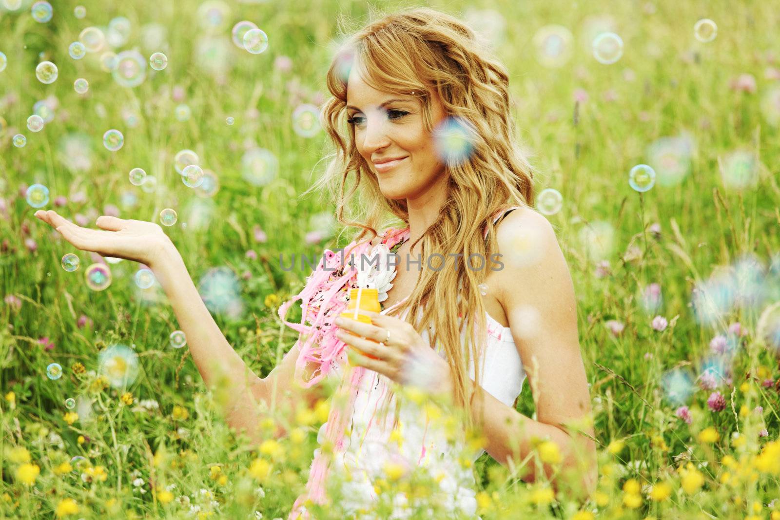  Blonde starts soap bubbles in a green field