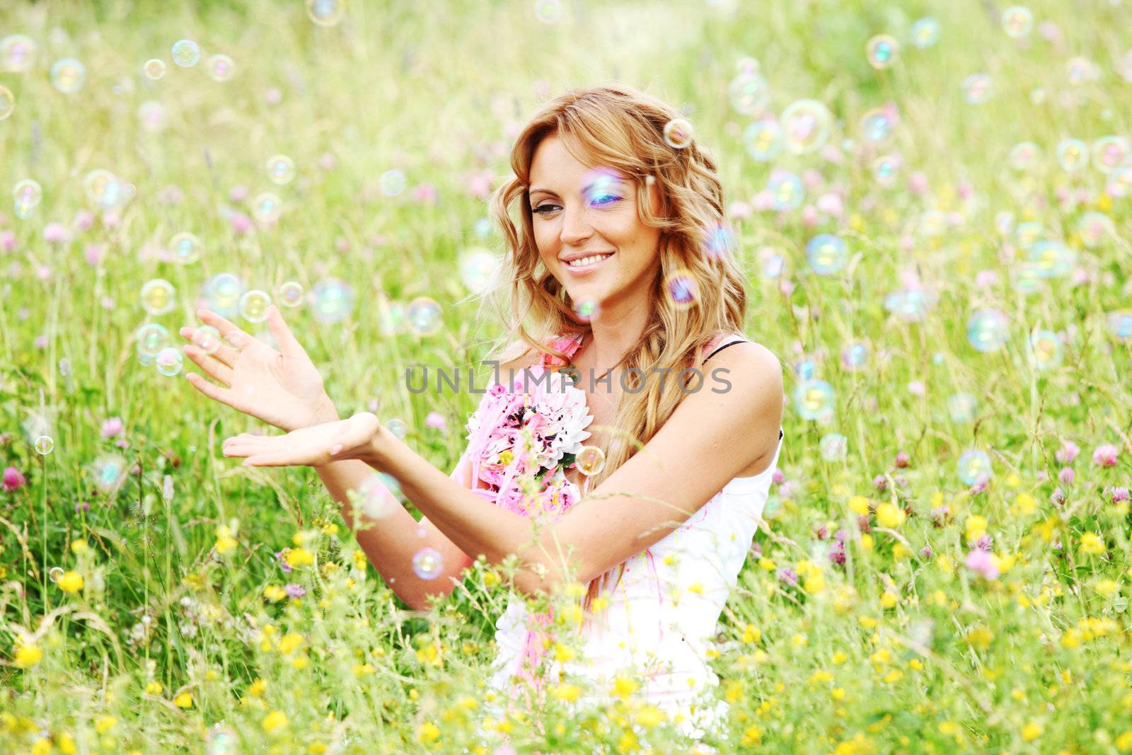  Blonde starts soap bubbles in a green field