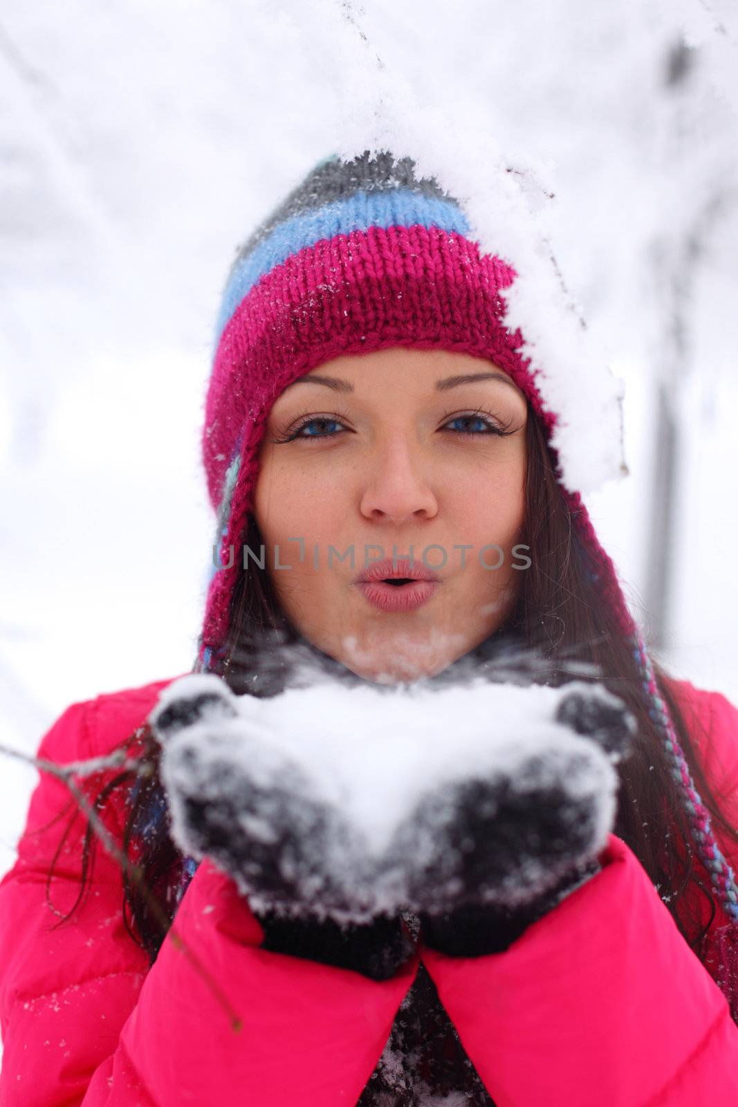 winter girl blow on snow in hands