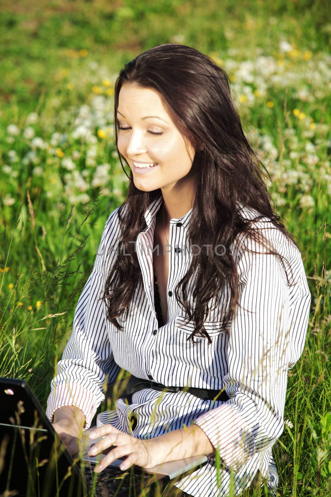 girl with laptop on green grass