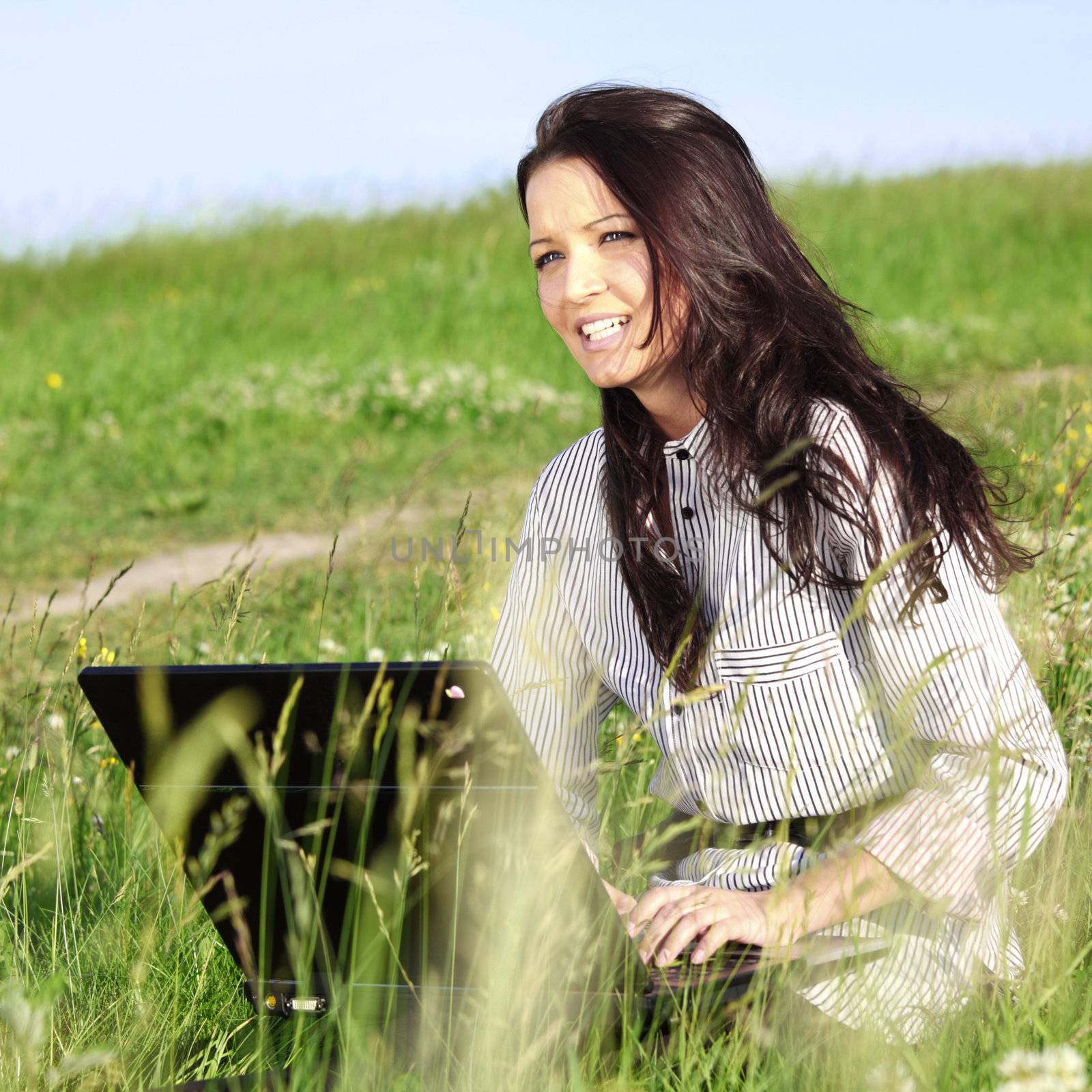 girl with laptop on green grass