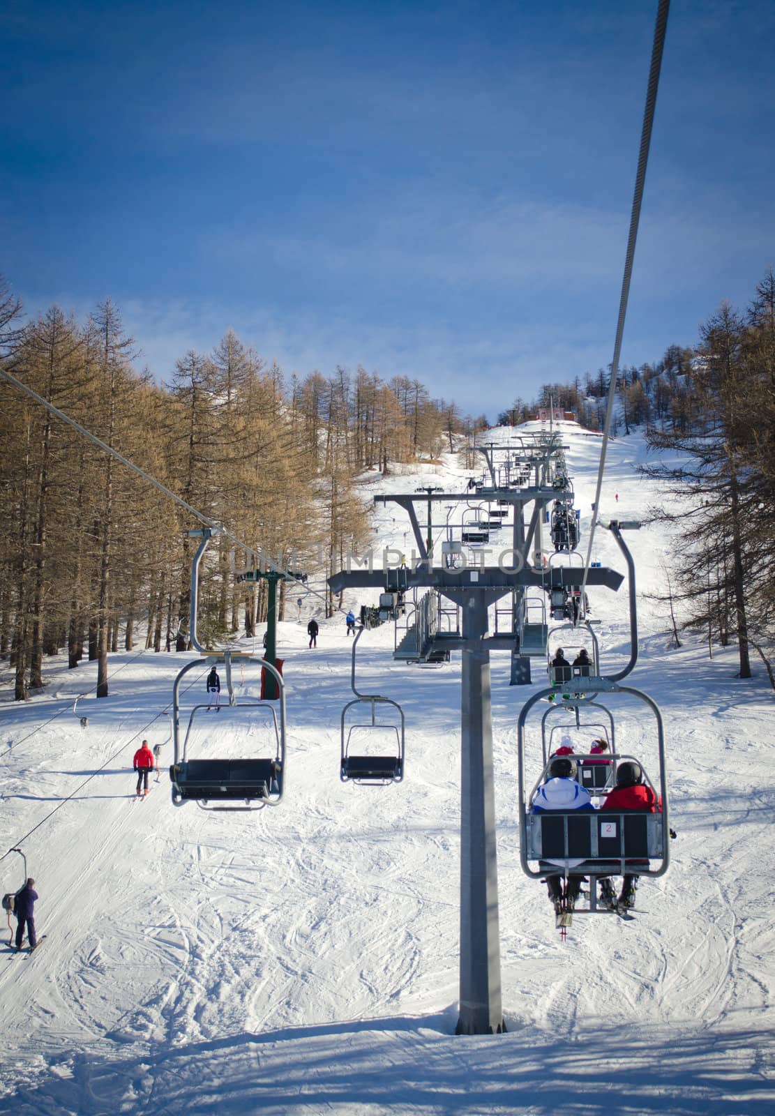 People and skiers on chairlift (aerial lift) and skilift in sunny day