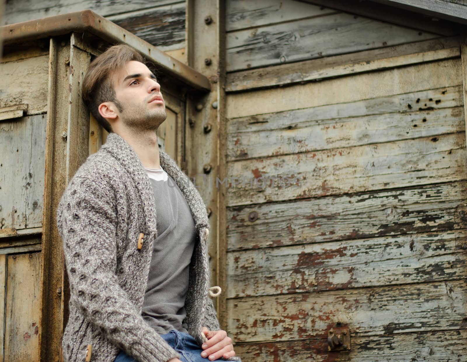 Attractive young man against rusty metal and wooden walls by artofphoto