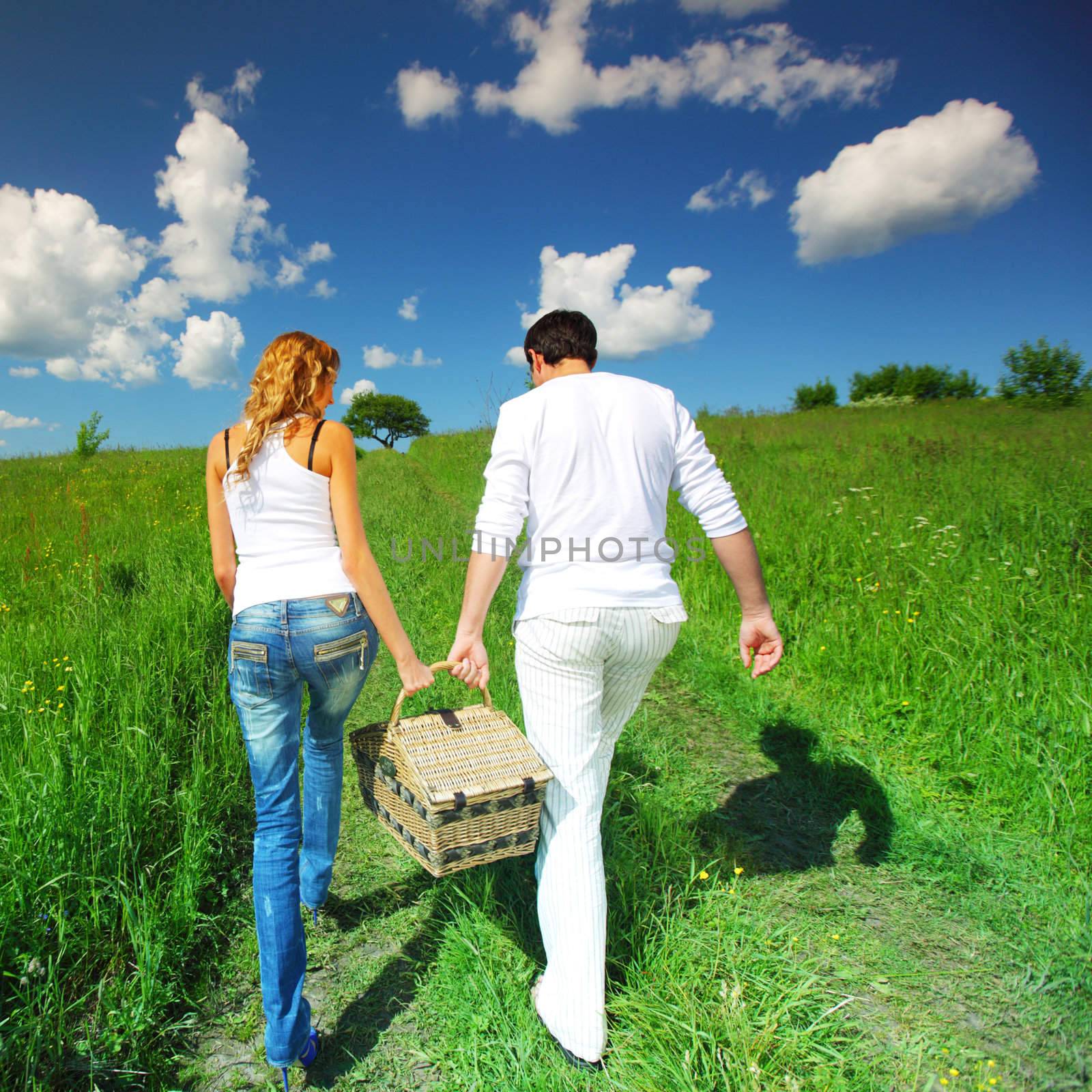 man and woman walk on picnic in green grass