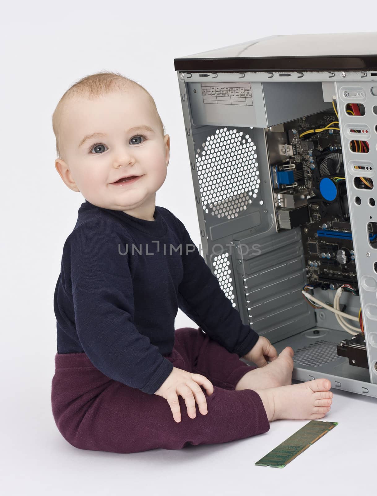 young child in blue shirt with open computer on neutral background