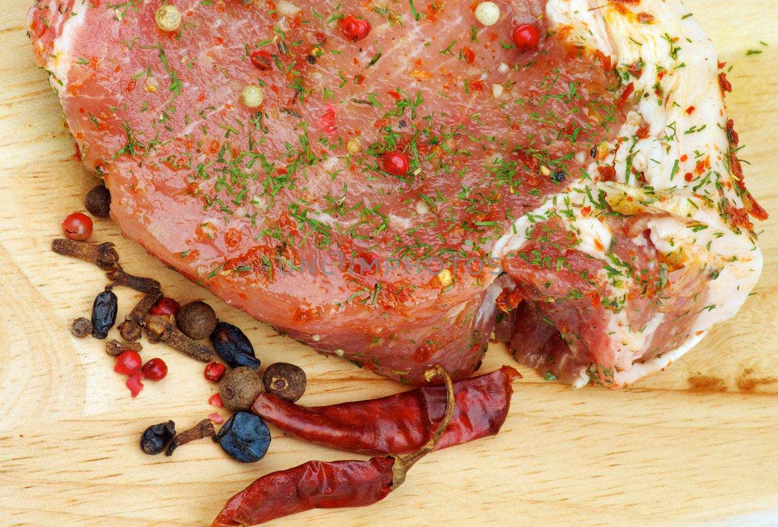 Marinated Raw Pork with Herbs, Greens and Spices closeup on Wooden Cutting Board